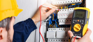 Electrician installing electric cable wires and fuse switch box. Multimeter in hands of electricians detail